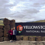 My husband and I standing next to the Yellowstone National park entrance sign at the north entrance