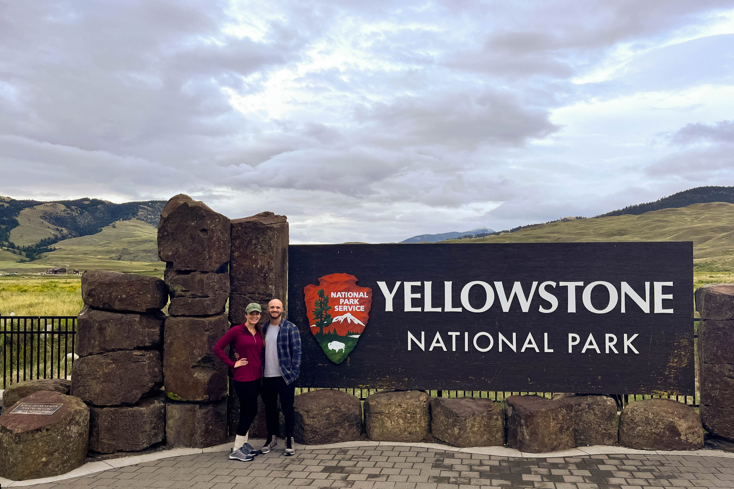 My husband and I standing next to the Yellowstone National park entrance sign at the north entrance