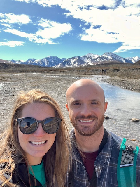 My husband and I along the riverbank of a braided river.